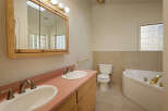 This charming bathroom boasts a double vanity with pink countertop and updated sink and faucet fixtures.