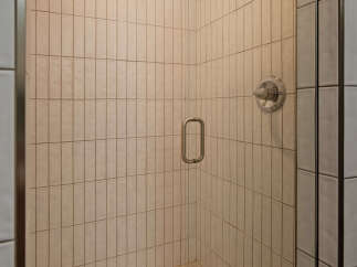 This stunning bathroom boasts a spacious shower with sleek glass enclosure and modern fixtures.