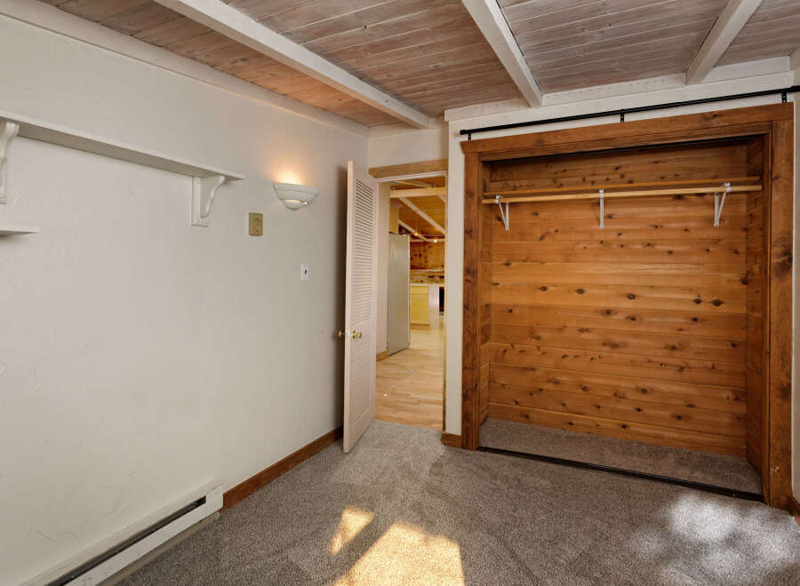 Cozy bedroom with built-in closet featuring wood paneling and a sliding door.