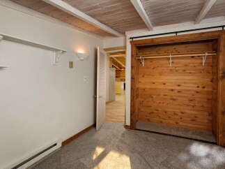 Cozy bedroom with built-in closet featuring wood paneling and a sliding door.