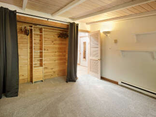 Cozy bedroom with built-in closet featuring wood paneling and shelving.