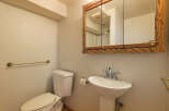 This charming bathroom boasts a classic pedestal sink and toilet, complemented by a wood-framed medicine cabinet.
