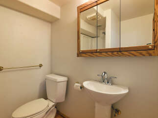 This charming bathroom boasts a classic pedestal sink and toilet, complemented by a wood-framed medicine cabinet.