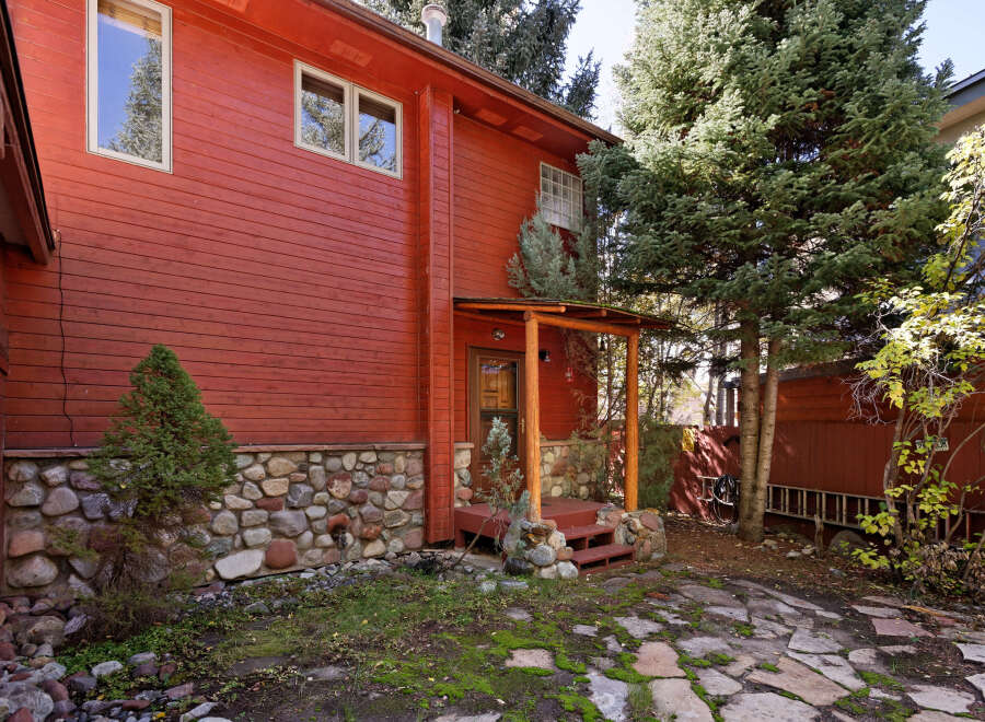This charming red cabin boasts a rustic stone foundation and a quaint wooden porch, perfect for enjoying the mountain air.