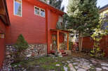This charming red cabin boasts a rustic stone foundation and a quaint wooden porch, perfect for enjoying the mountain air.