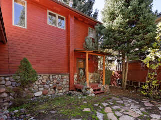 This charming red cabin boasts a rustic stone foundation and a quaint wooden porch, perfect for enjoying the mountain air.