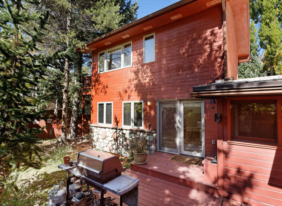 This charming red wooden house boasts a spacious deck perfect for outdoor entertaining, complete with a built-in grill.
