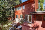 This charming red wooden house boasts a spacious deck perfect for outdoor entertaining, complete with a built-in grill.