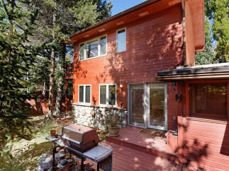 This charming red wooden house boasts a spacious deck perfect for outdoor entertaining, complete with a built-in grill.