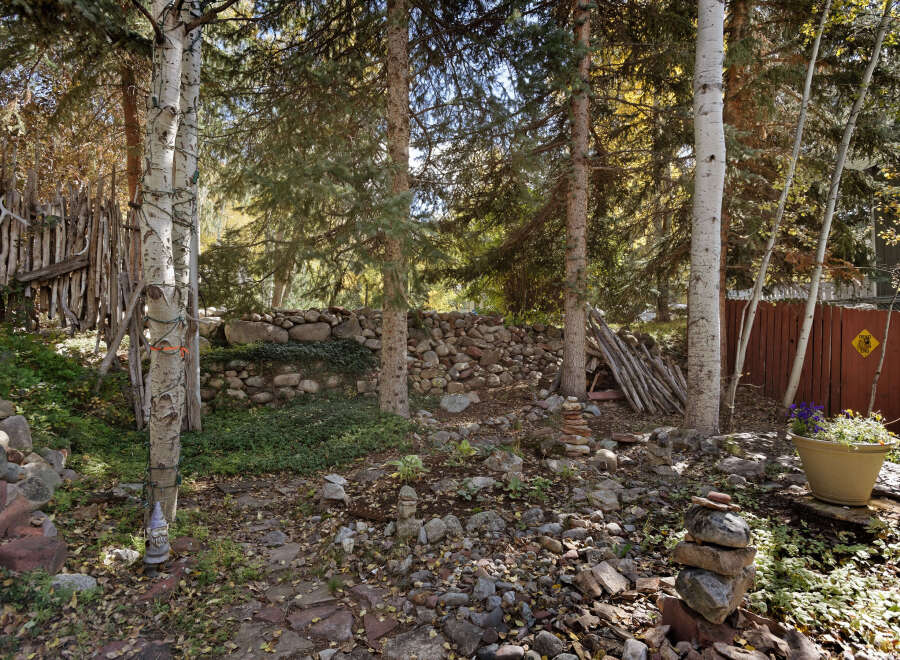 Discover a secluded oasis nestled in the woods, featuring a unique rock wall and whimsical garden art.