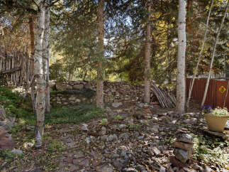 Discover a secluded oasis nestled in the woods, featuring a unique rock wall and whimsical garden art.