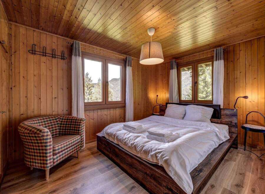 Cozy bedroom with wooden walls and ceiling, creating a warm and inviting atmosphere.
