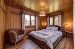 Cozy bedroom with wooden walls and ceiling, creating a warm and inviting atmosphere.