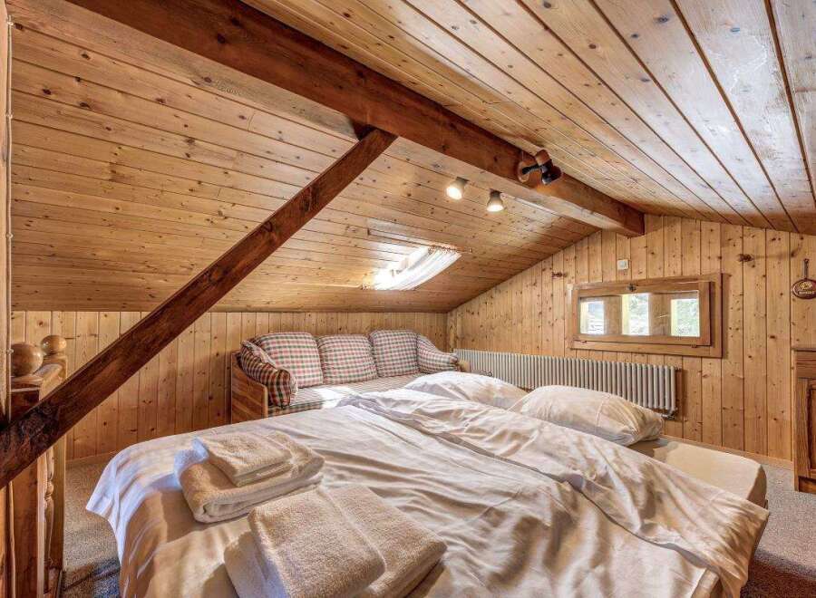 Cozy cabin bedroom with wooden walls and ceiling.