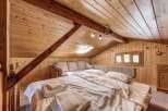 Cozy cabin bedroom with wooden walls and ceiling.