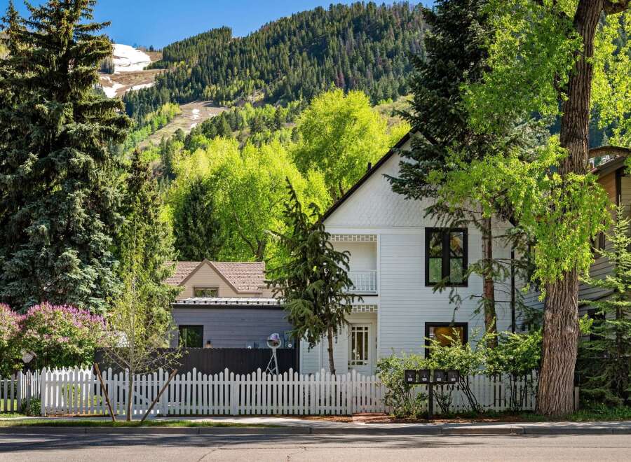 Charming white house nestled in a mountain setting with a white picket fence.