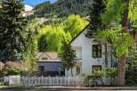 Charming white house nestled in a mountain setting with a white picket fence.