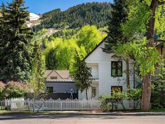 Charming white house nestled in a mountain setting with a white picket fence.