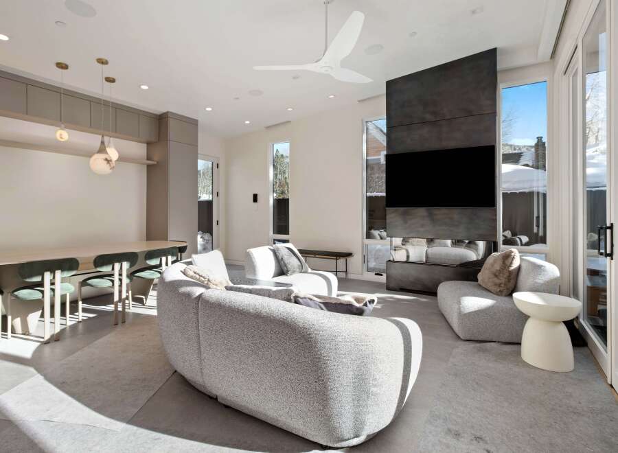 This stunning modern living room boasts a sleek design with floor-to-ceiling windows offering breathtaking views, a cozy curved sofa, and a unique fireplace feature.