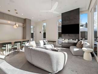 This stunning modern living room boasts a sleek design with floor-to-ceiling windows offering breathtaking views, a cozy curved sofa, and a unique fireplace feature.