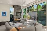 Modern living room with a stunning fireplace and large sliding glass doors leading to a patio with a grill.