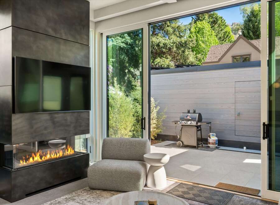 This stunning home boasts a modern fireplace and large sliding glass doors that open to a private patio with a built-in grill.