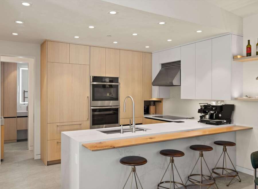 This stunning kitchen boasts modern cabinetry, high-end stainless steel appliances, and a sleek island with a wood countertop.
