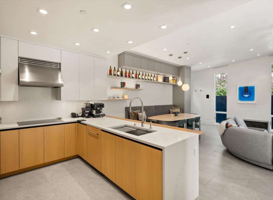 This stunning modern home boasts an open-concept kitchen with sleek cabinetry and high-end appliances, seamlessly flowing into a spacious living area.