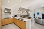 This stunning modern home boasts an open-concept kitchen with sleek cabinetry and high-end appliances, seamlessly flowing into a spacious living area.