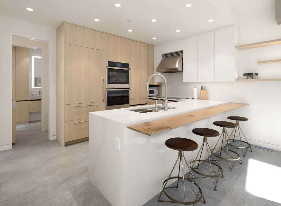 This stunning kitchen boasts sleek, modern cabinetry, high-end stainless steel appliances, and a spacious island with a breakfast bar.