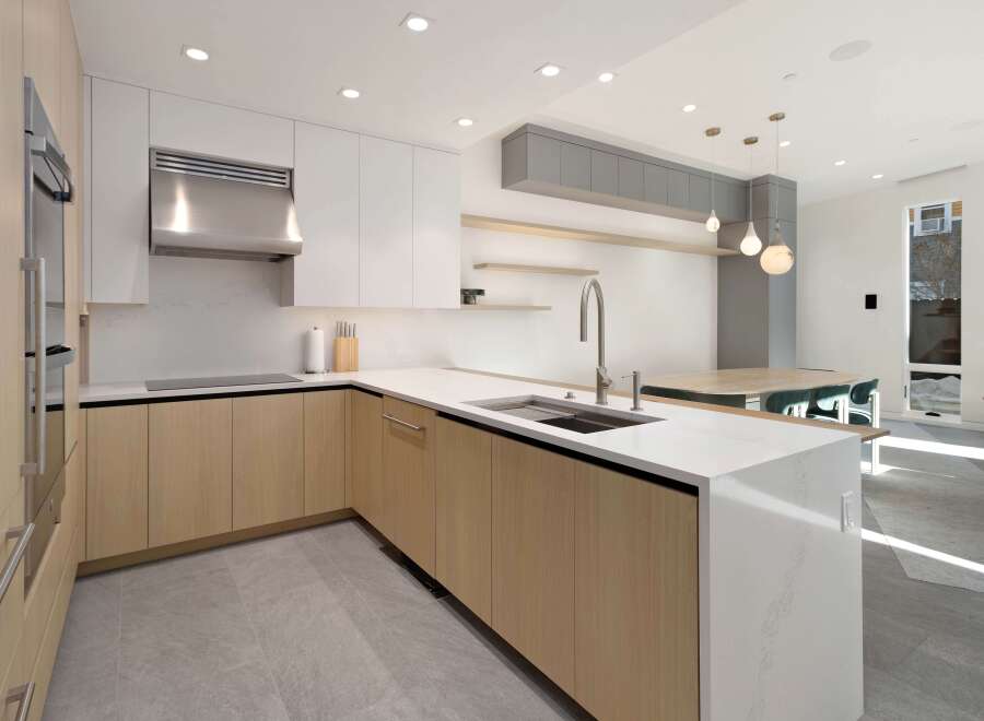 This stunning kitchen boasts modern light oak cabinetry, sleek stainless steel appliances, and a spacious island with waterfall countertops.