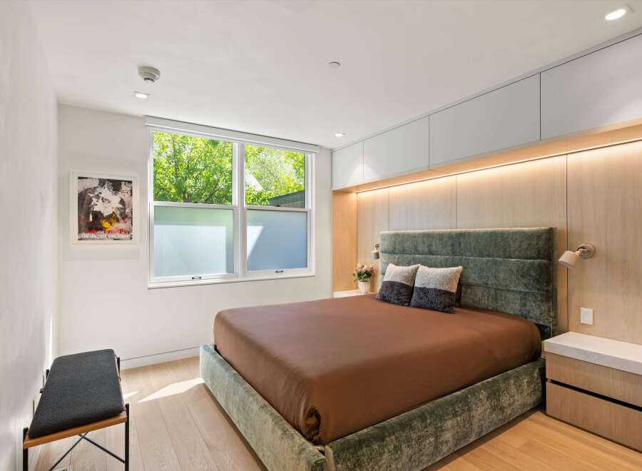 This stunning bedroom boasts a plush velvet bed, custom wood paneling, and built-in cabinetry, creating a luxurious and serene atmosphere.