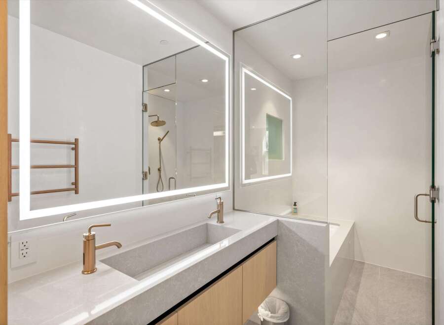This stunning bathroom boasts a sleek, modern design with a frameless glass shower enclosure and a built-in bathtub.