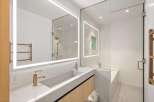 This stunning bathroom boasts a sleek, modern design with a frameless glass shower enclosure and a built-in bathtub.