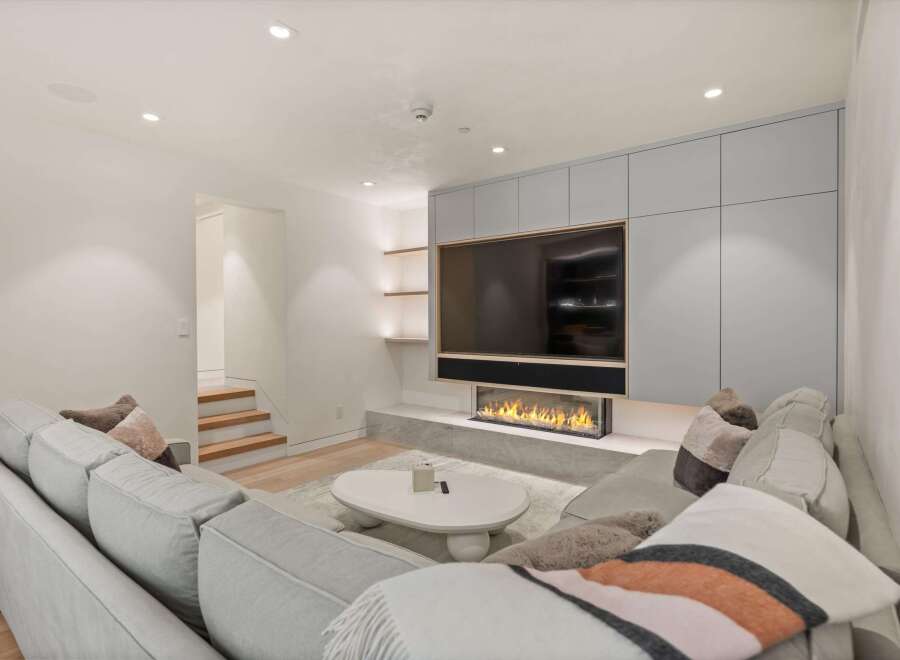 Modern living room with built-in entertainment center featuring a large TV and linear fireplace.