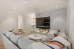Modern living room with built-in entertainment center featuring a large TV and linear fireplace.