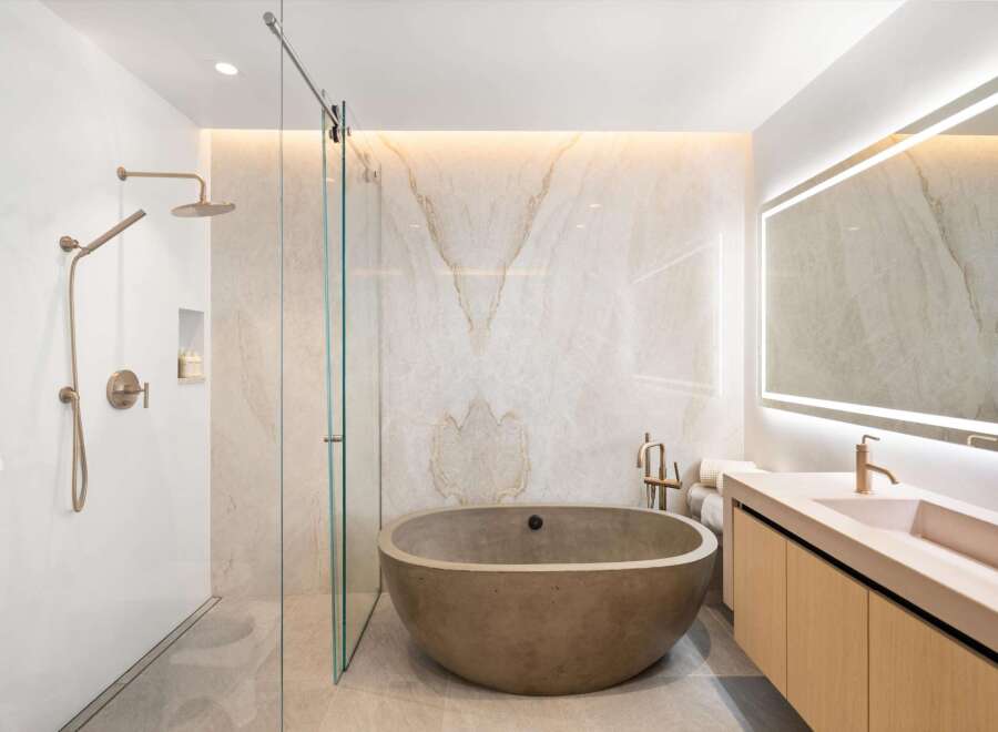 Luxurious bathroom boasts a freestanding concrete tub and a frameless glass shower enclosure.