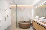 Luxurious bathroom boasts a freestanding concrete tub and a frameless glass shower enclosure.