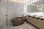 Luxurious bathroom boasts a freestanding concrete tub and a double vanity with sleek wooden cabinets.