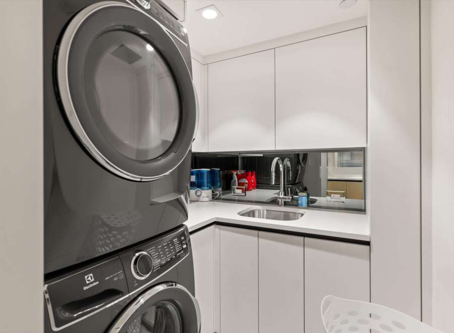 This stunning laundry room boasts modern, sleek appliances and ample storage.
