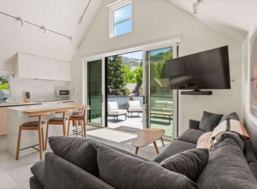Modern mountain condo with open floor plan, kitchen island, and access to a private deck with stunning views.