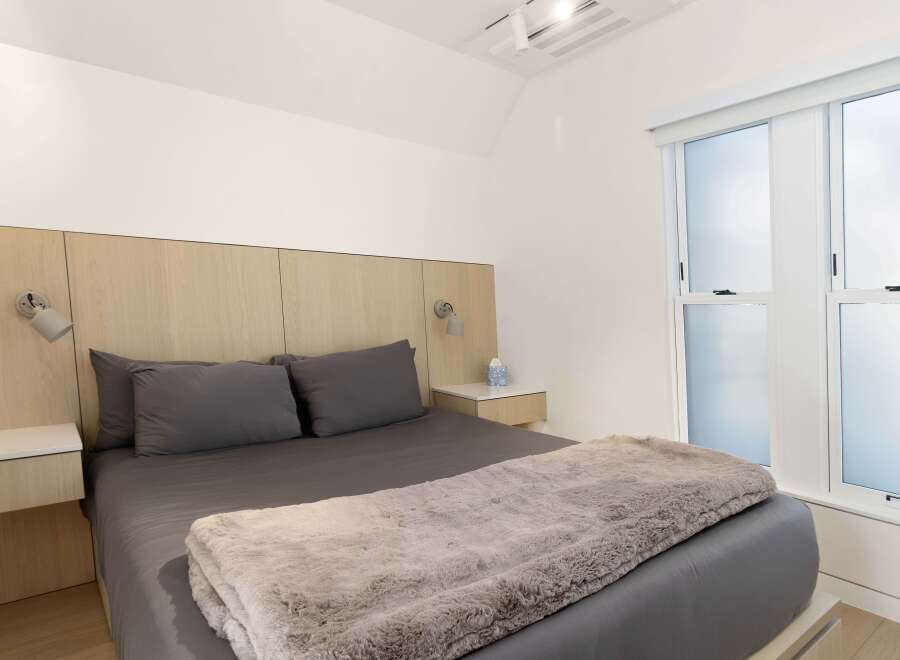 Modern bedroom with a light wood accent wall, plush gray bedding, and a cozy faux fur throw.