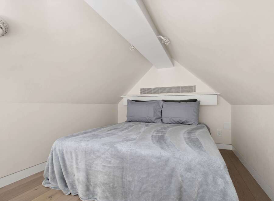 Cozy attic bedroom with a plush gray blanket and matching pillows.
