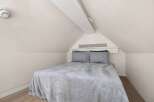 Cozy attic bedroom with a plush gray blanket and matching pillows.