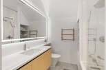 This stunning bathroom boasts a modern design with sleek white finishes and light oak cabinetry.