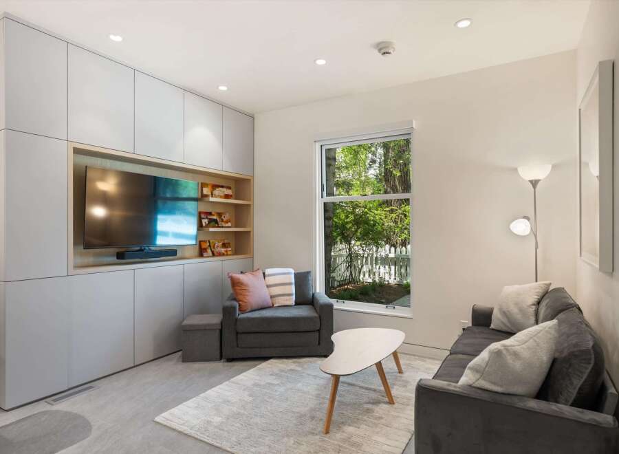 Modern living room with built-in entertainment center and large window overlooking backyard.