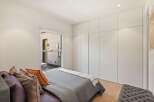This bedroom boasts a serene atmosphere with its minimalist design and large window offering ample natural light.