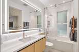 This stunning bathroom boasts a modern design with a sleek, illuminated mirror and a spacious walk-in shower.