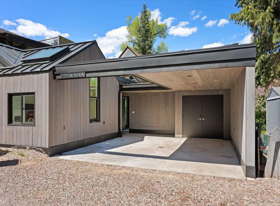 This stunning property boasts a modern design with a sleek, gray exterior and a spacious carport.