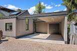 This stunning property boasts a modern design with a sleek, gray exterior and a spacious carport.